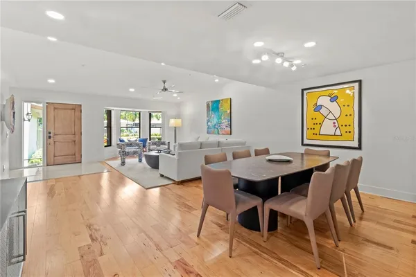 a living room with dining table and couches with wooden floor