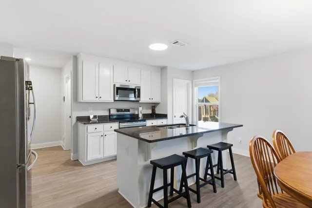 a kitchen with stainless steel appliances granite countertop a stove a sink dishwasher a refrigerator with a dining table and chairs