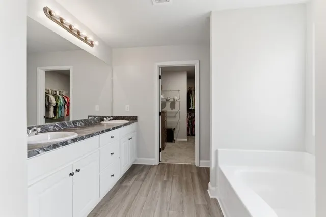 a bathroom with a granite countertop bathtub a sink and a mirror