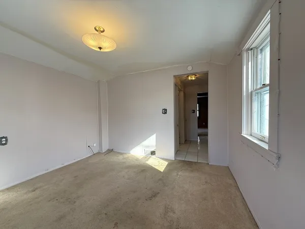 a view of an empty room with window and chandelier