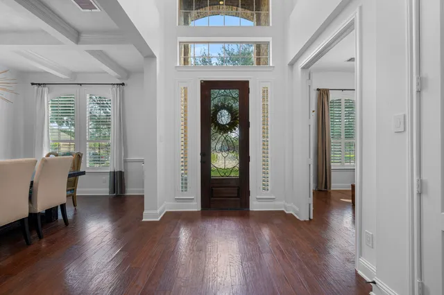 an empty room with wooden floor chandelier and windows