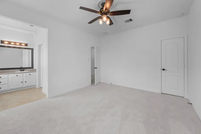an empty room with chandelier and a ceiling fan