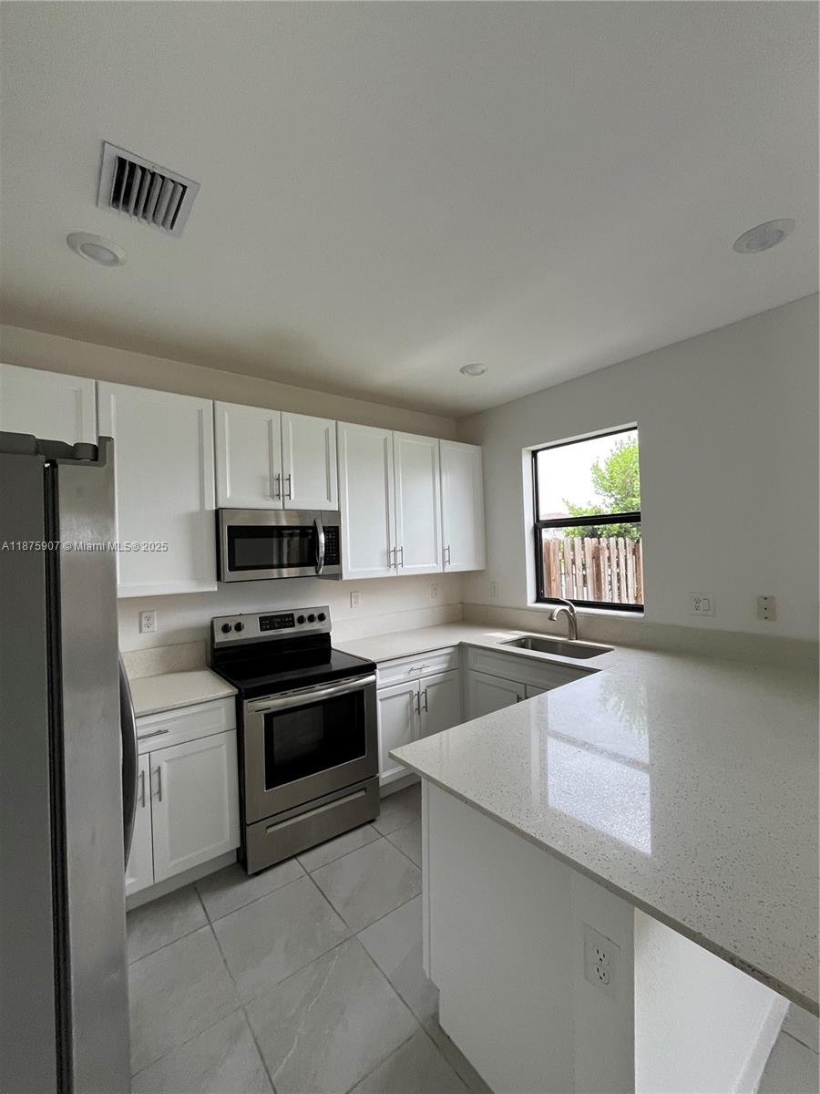 10008 Southwest 228th Terrace Miami, FL 33190 - Photo 14 of 46 a kitchen with stainless steel appliances a refrigerator sink and stove