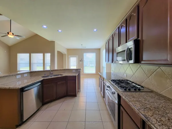 a kitchen with stainless steel appliances granite countertop a sink stove and microwave