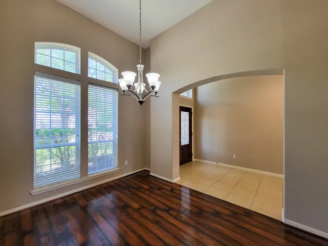 a view of an empty room with a window and kitchen area