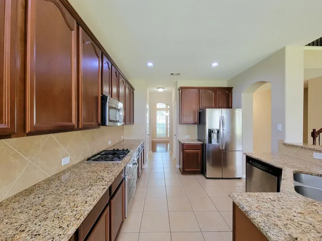 a kitchen with stainless steel appliances granite countertop a sink and a refrigerator
