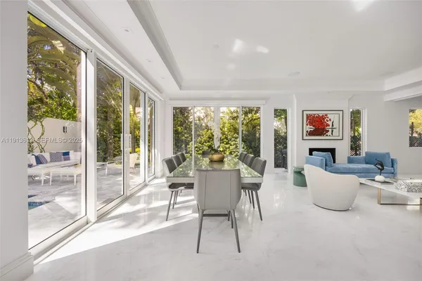 a view of a dining room with furniture large windows and backyard