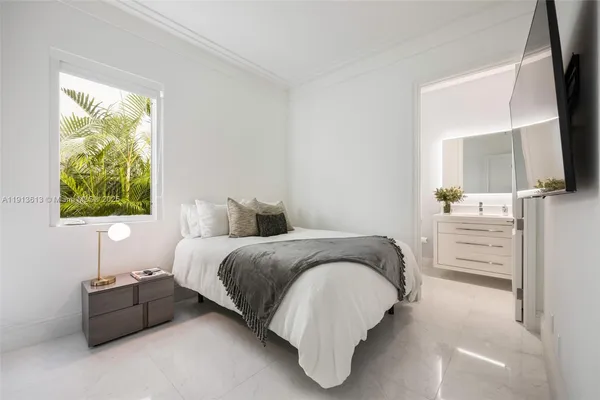 a spacious bedroom with a bed and a flat tv screen on dresser