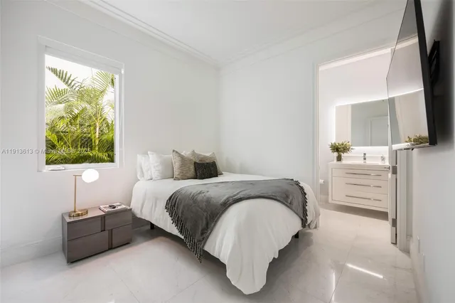 a spacious bedroom with a bed and a flat tv screen on dresser