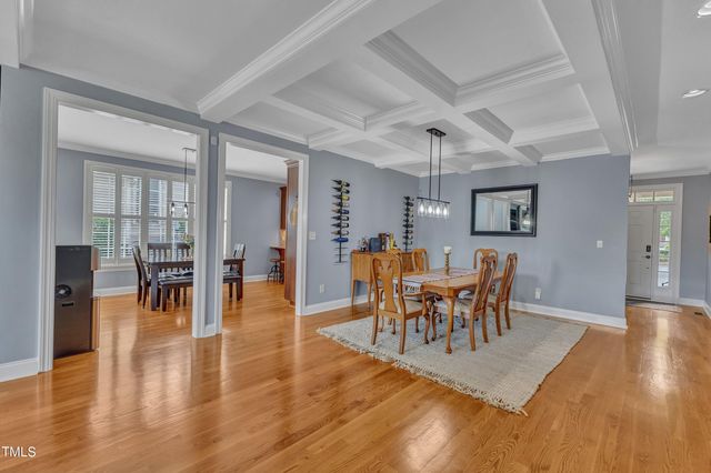 a dining room with wooden floor a chandelier a glass table and chairs