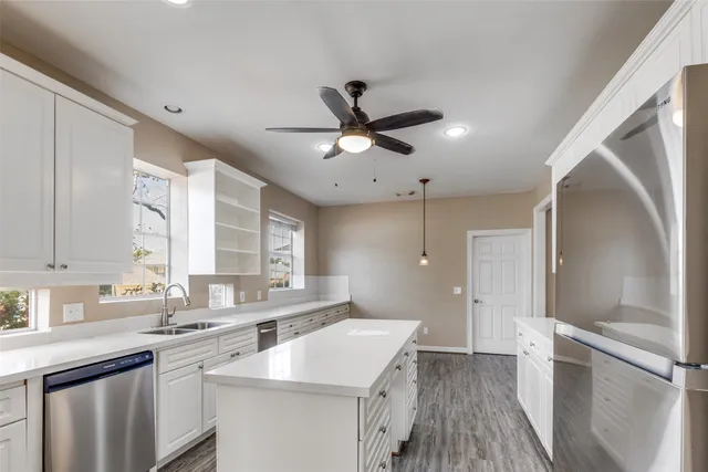 an empty room with chandelier fan and windows