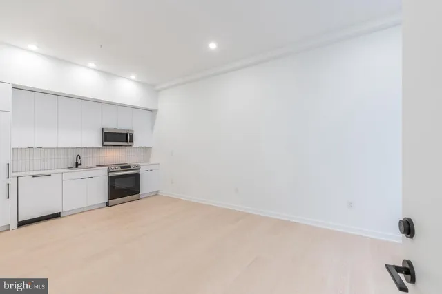 a large kitchen with white cabinets and stainless steel appliances