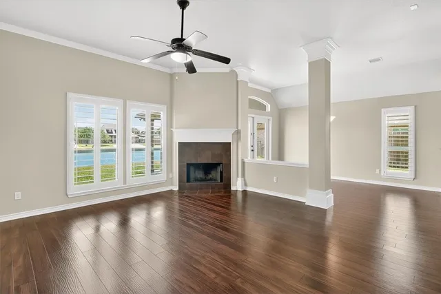 a view of an empty room with wooden floor fireplace and a window