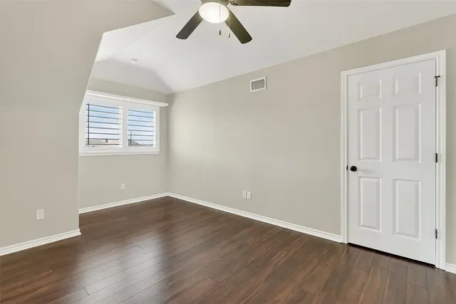 an empty room with wooden floor closet and windows