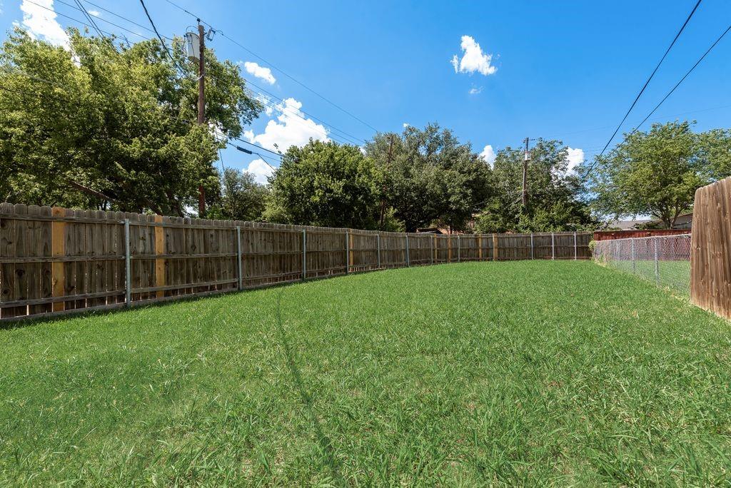 219 West Rochelle Road Irving, TX 75062 - Photo 28 of 29 Spacious backyard featuring a manicured lawn, a full wood privacy fence, and a partial chain-link fence