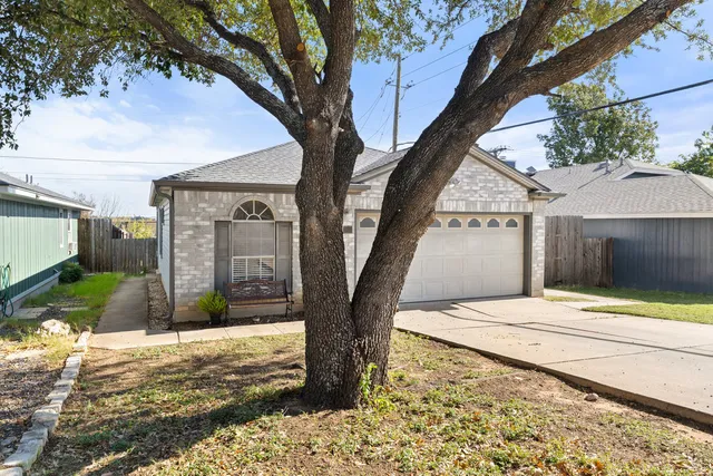 a view of a yard in front of a house with large tree
