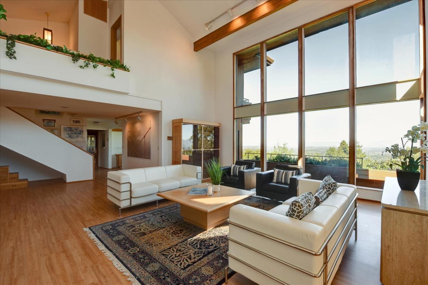 a living room with furniture large windows and wooden floor