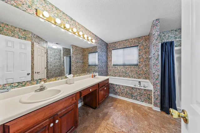 a bathroom with a sink double vanity granite tub shower and a mirror
