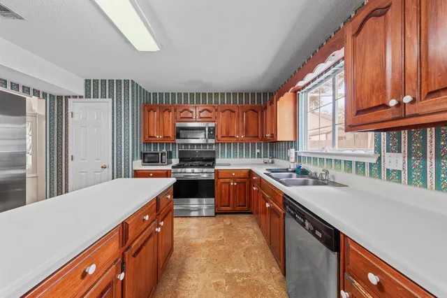 a kitchen with stainless steel appliances a sink window and cabinets