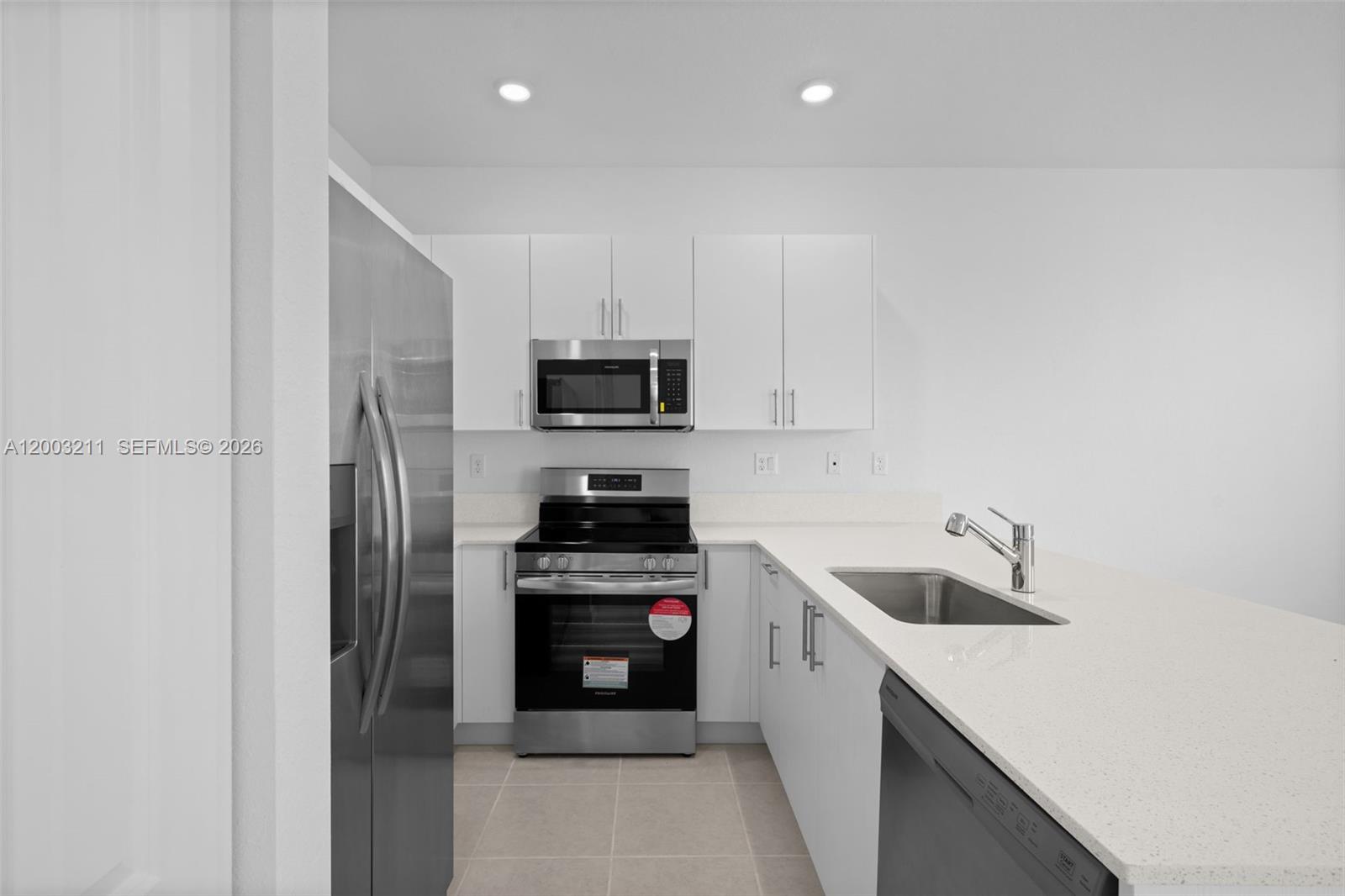 715 Southeast 15th Street Homestead, FL 33034 - Photo 13 of 38 a kitchen with a sink white cabinets and stainless steel appliances
