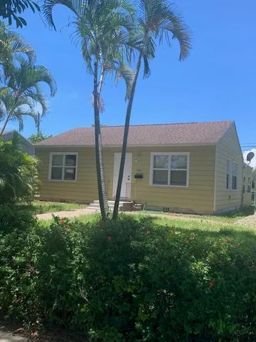 a backyard of a house with plants and large tree