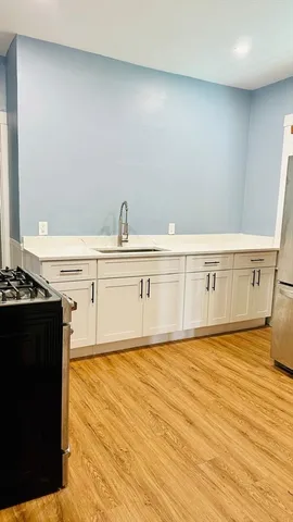 a view of an empty room with wooden floor and a sink