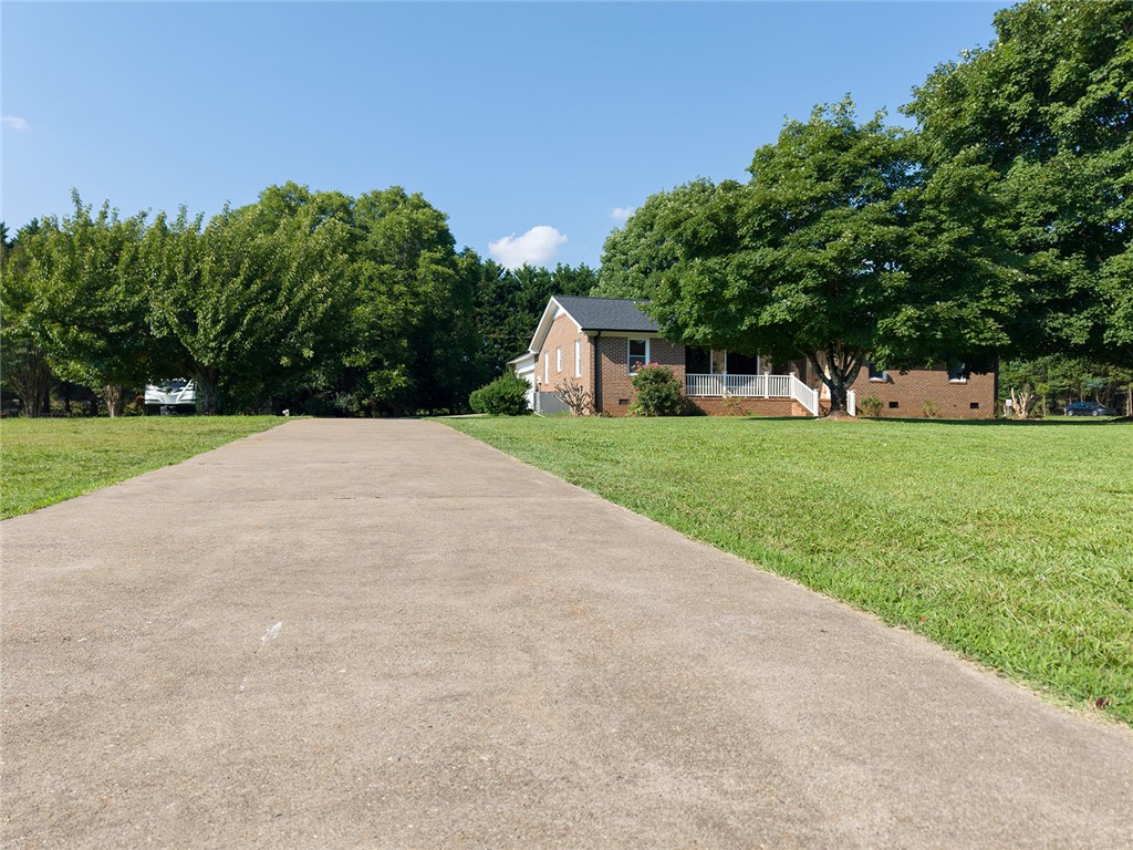 902 Cherokee Road Pelzer, SC 29669 - Photo 37 of 38 A lengthy concrete driveway leads to a classic brick residence nestled among mature shade trees.
