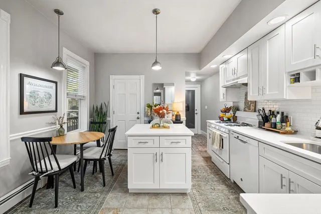 a kitchen with a dining table chairs stove and white cabinets