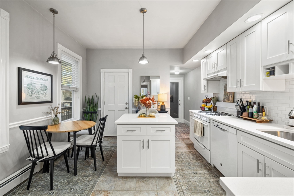 37 M Street Boston, MA 02127 - Photo 11 of 42 a kitchen with a dining table chairs stove and white cabinets