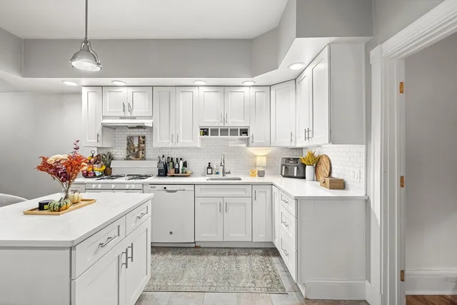 a kitchen with kitchen island granite countertop a sink cabinets and stainless steel appliances