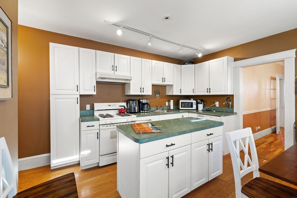 37 M Street Boston, MA 02127 - Photo 21 of 42 a kitchen with stainless steel appliances granite countertop a refrigerator a sink dishwasher a stove and white countertops with wooden floor
