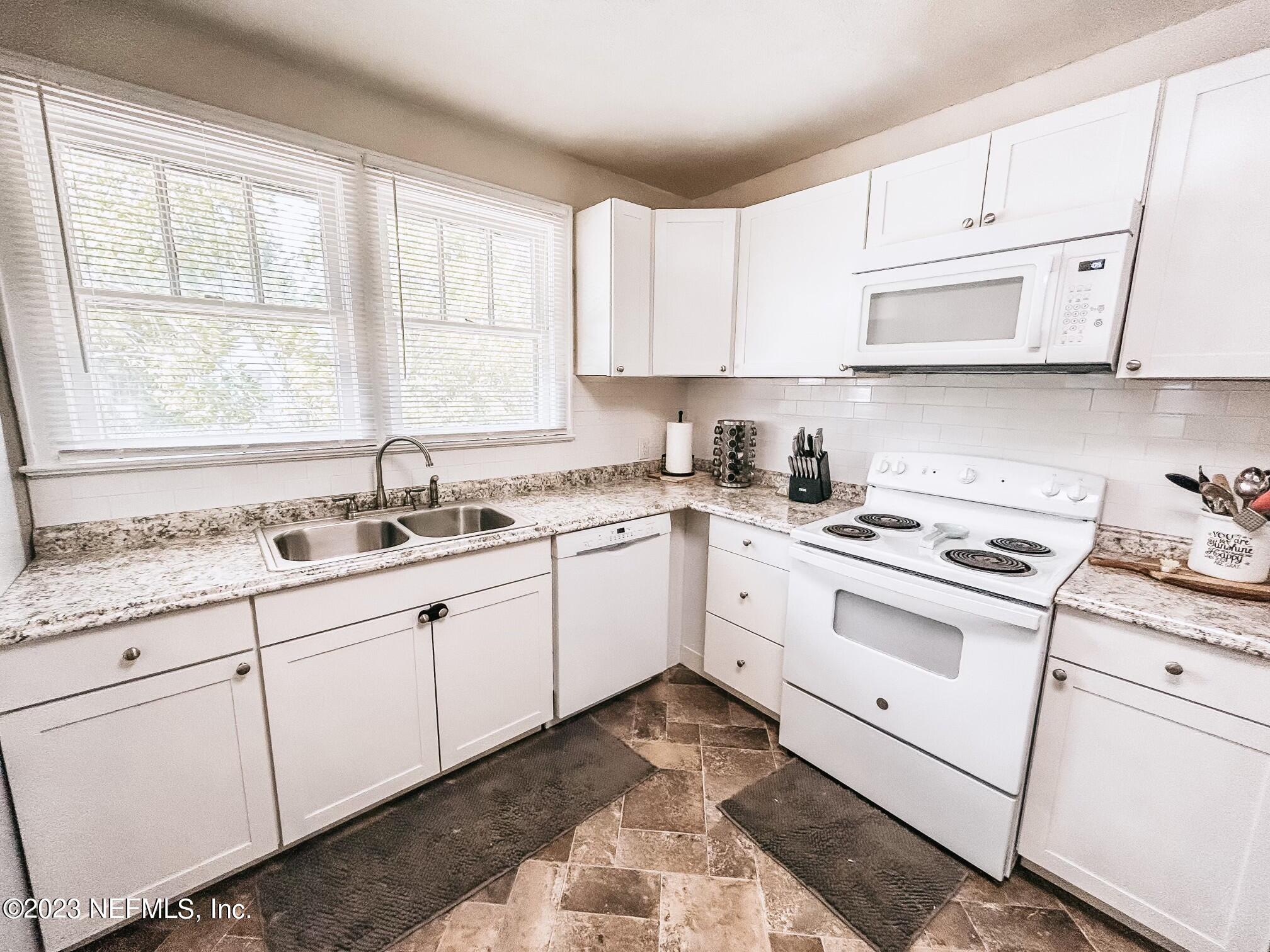 224 Benham Street Palatka, FL 32177 - Photo 6 of 15 a kitchen with granite countertop white cabinets and white appliances