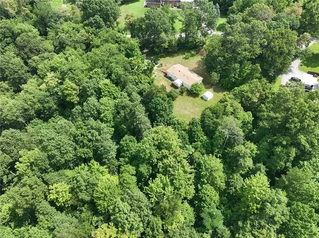 an aerial view of residential house with outdoor space and trees all around