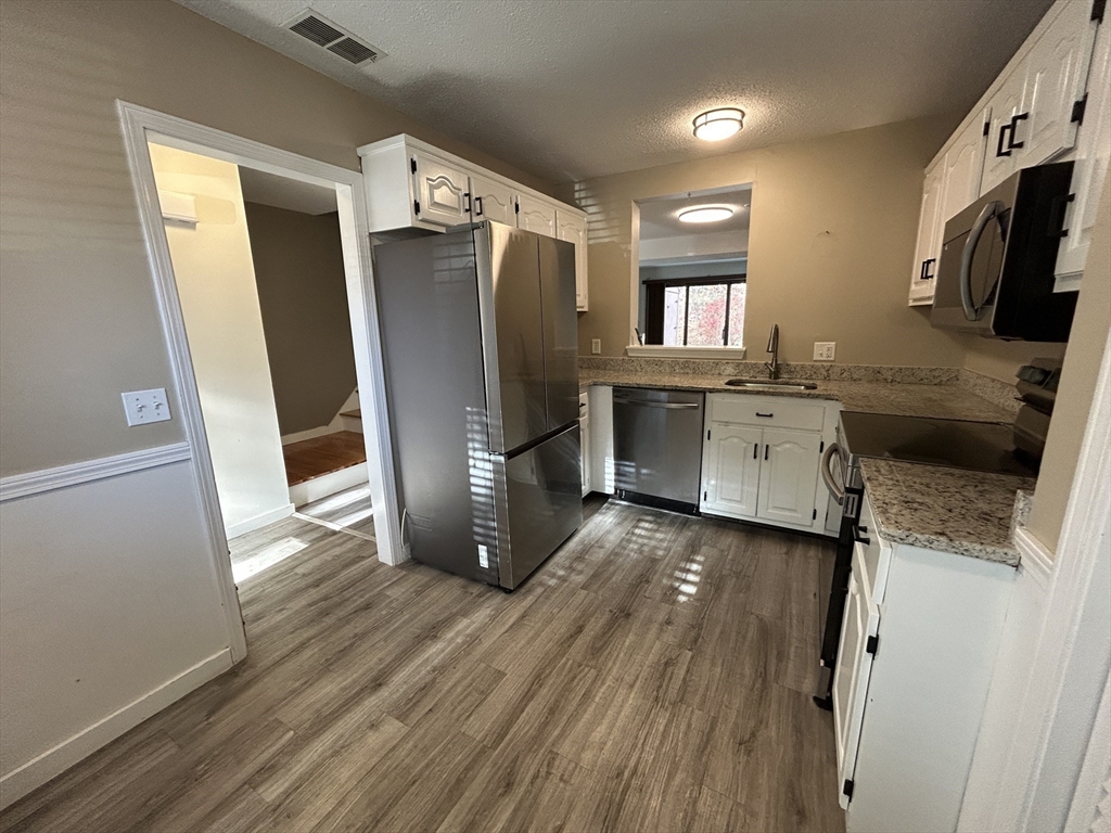 28 Apple Tree Hill Road, Unit 28 Hopkinton, MA 01748 - Photo 2 of 20 a kitchen with stainless steel appliances granite countertop a refrigerator a stove a sink dishwasher and a microwave oven with wooden floor