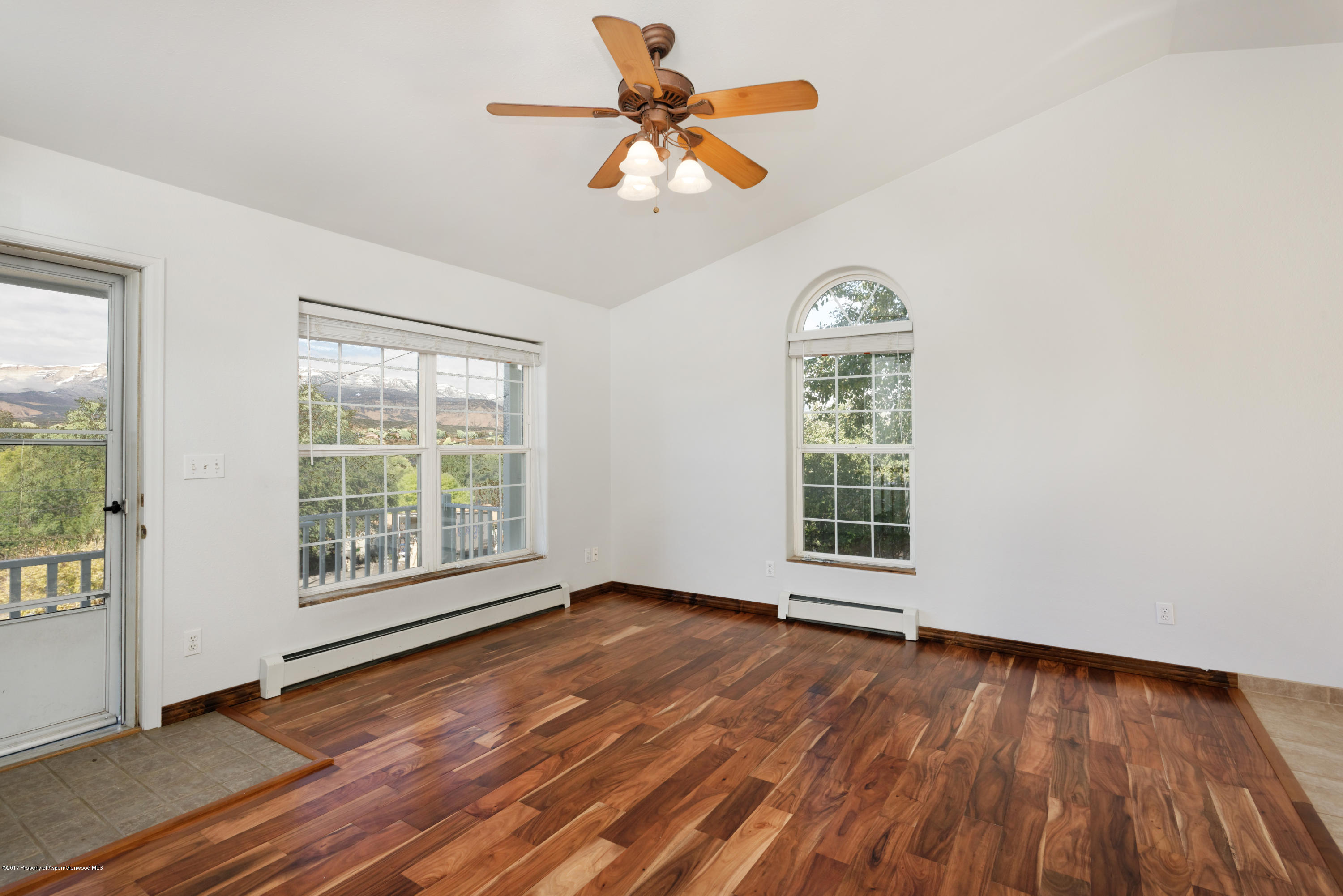 776 Munro Avenue Rifle, CO 81650 - Photo 11 of 24 an empty room with wooden floor chandelier fan and windows
