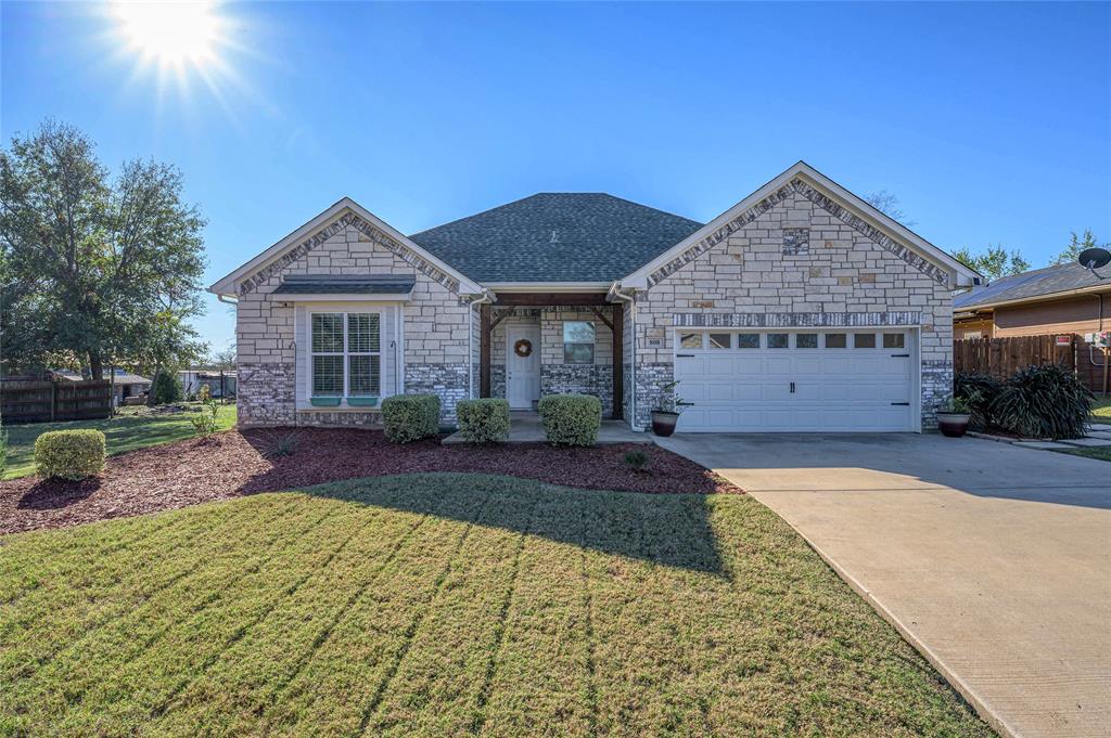 View of front of house featuring stone siding, concrete driveway, a garage, and roof with shingles