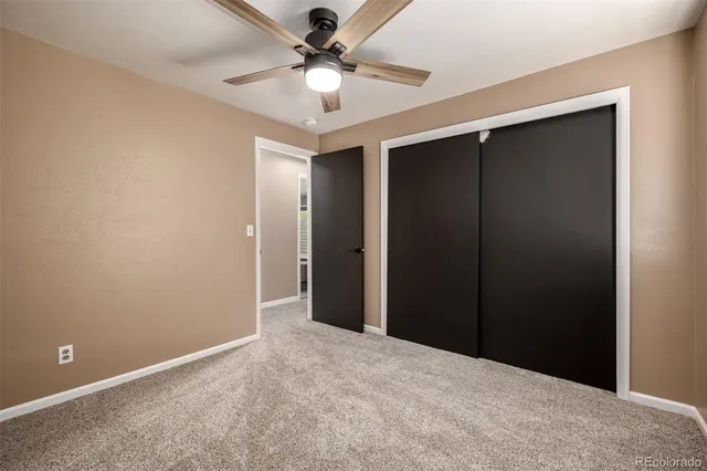 an empty room with closet and a chandelier fan
