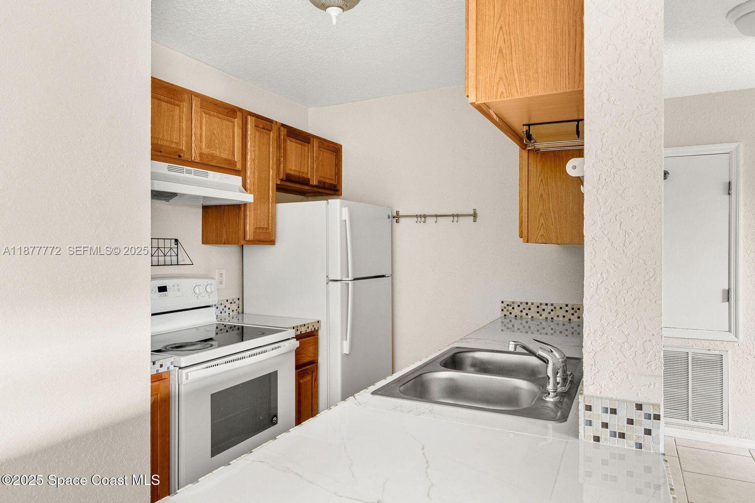 220 Columbia Drive, Unit 31 Cape Canaveral, FL 32920 - Photo 15 of 23 a kitchen with stainless steel appliances a refrigerator sink and stove