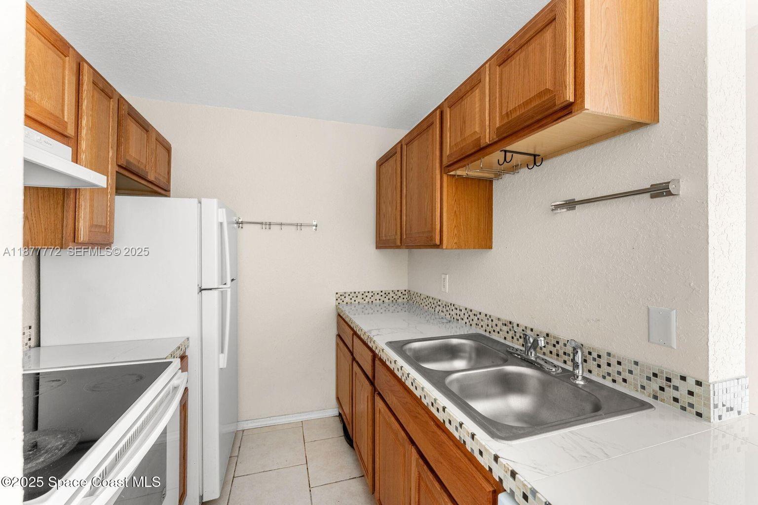 220 Columbia Drive, Unit 31 Cape Canaveral, FL 32920 - Photo 17 of 23 a kitchen with stainless steel appliances granite countertop a sink and a refrigerator