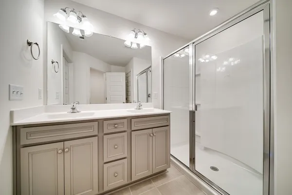 a bathroom with a double vanity sink mirror and shower