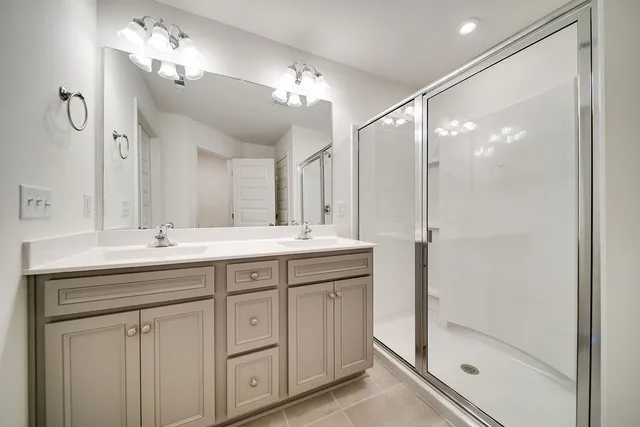 a bathroom with a double vanity sink mirror and shower