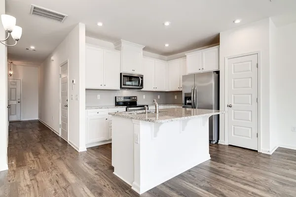 a kitchen with kitchen island a refrigerator cabinets and wooden floor