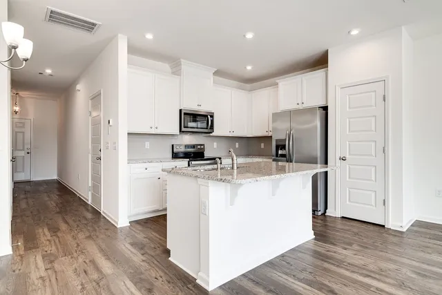 a kitchen with kitchen island a refrigerator cabinets and wooden floor