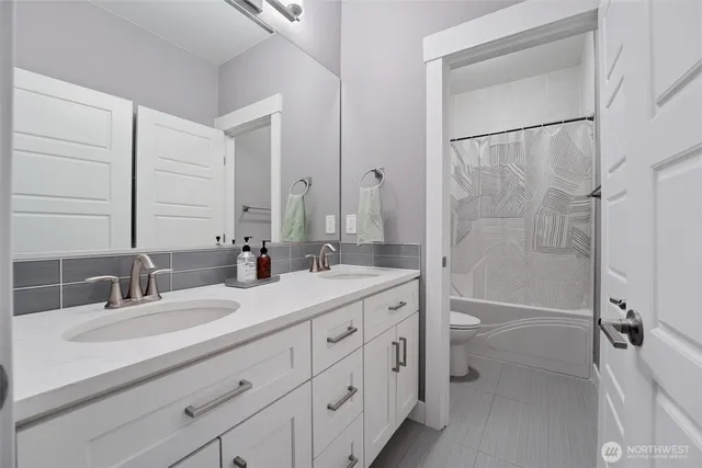 a bathroom with a double vanity sink toilet mirror and bathtub