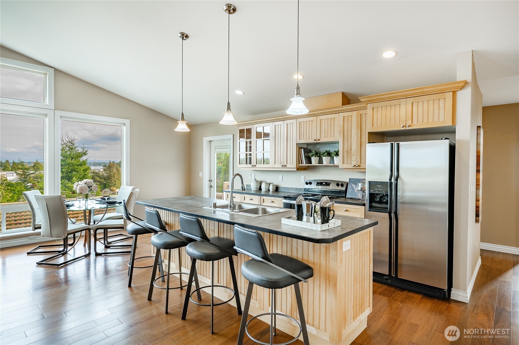 8124 Comox Road Blaine, WA 98230 - Photo 7 of 31 a kitchen with stainless steel appliances granite countertop a table chairs refrigerator and wooden floor