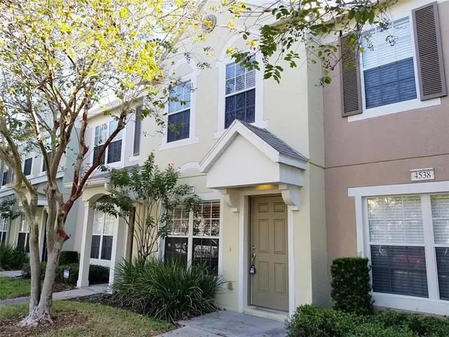 a front view of a house with plants and trees