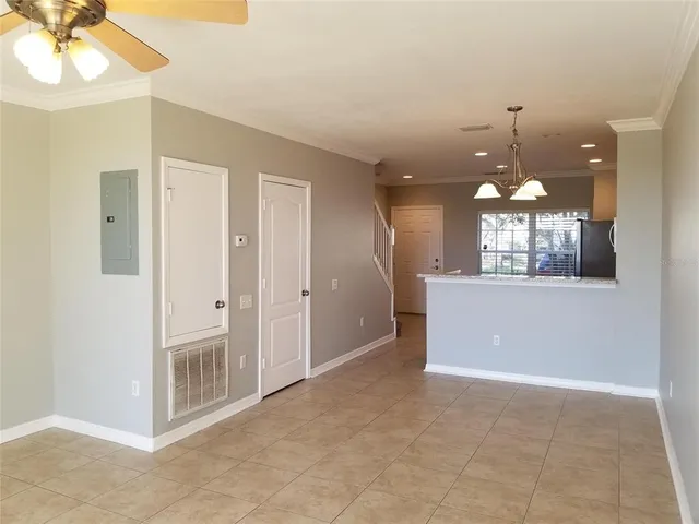 a view of a room with a chandelier fan and kitchen view