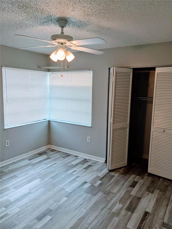 5327 Baldock Avenue Spring Hill, FL 34608 - Photo 14 of 18 an empty room with wooden floor chandelier fan and windows