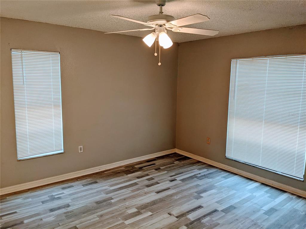 5327 Baldock Avenue Spring Hill, FL 34608 - Photo 4 of 18 an empty room with wooden floor fan and windows