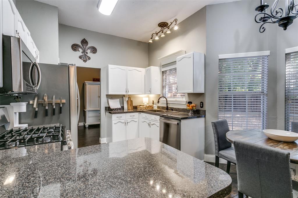 2133 Rim Rock Drive Keller, TX 76248 - Photo 20 of 37 Kitchen with stainless steel appliances, dark stone counters, white cabinetry, dark wood finished floors, and a chandelier